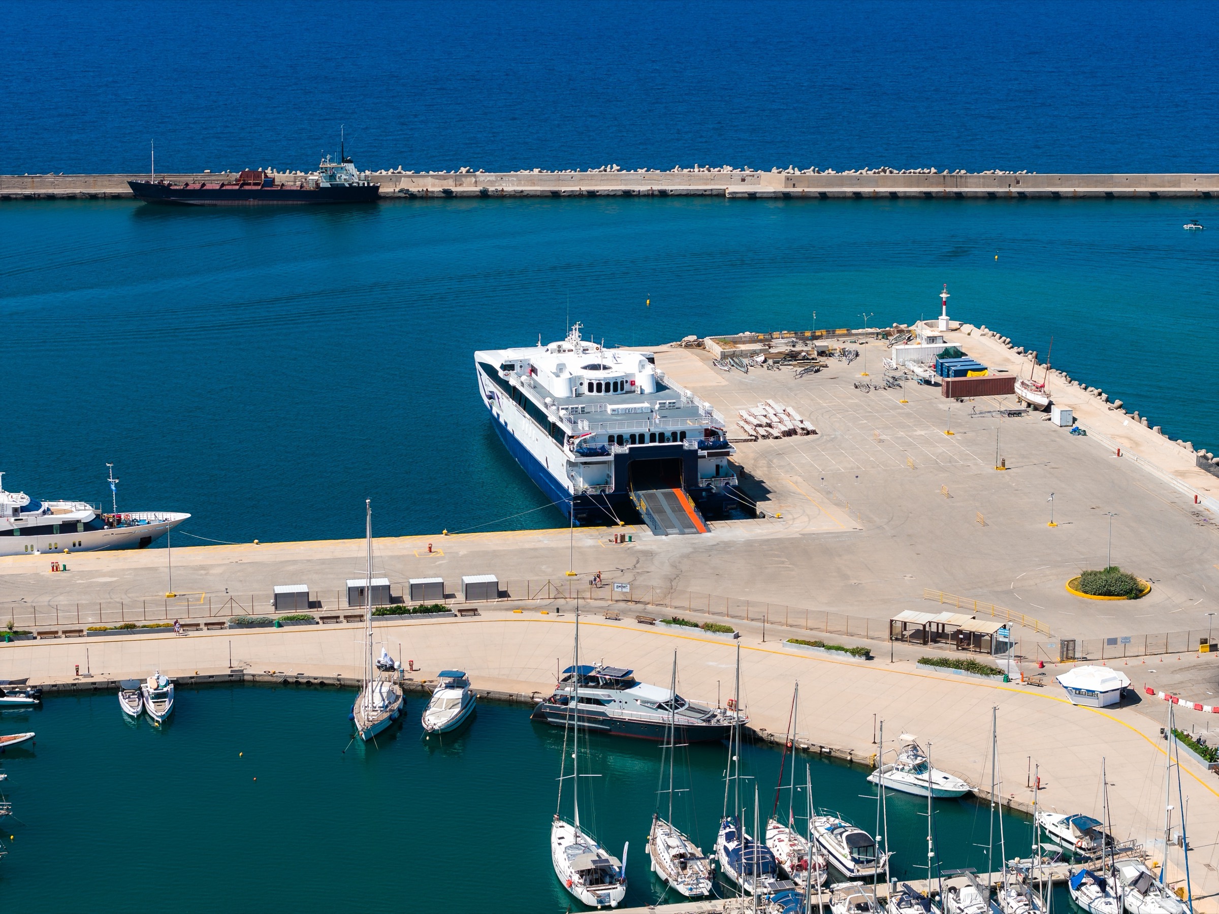 Aerial view of a ferry with its stern ramp open at the pier of a Mediterranean port